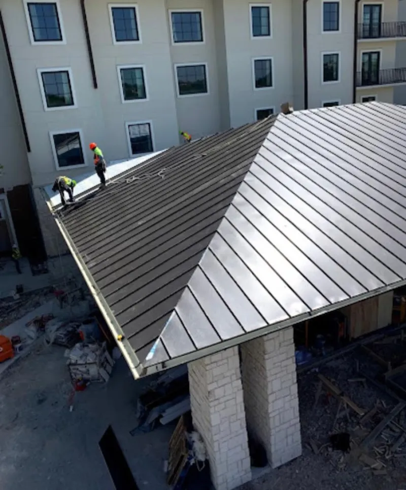Crew installing standing seam metal roof panels on a commercial project in Marion